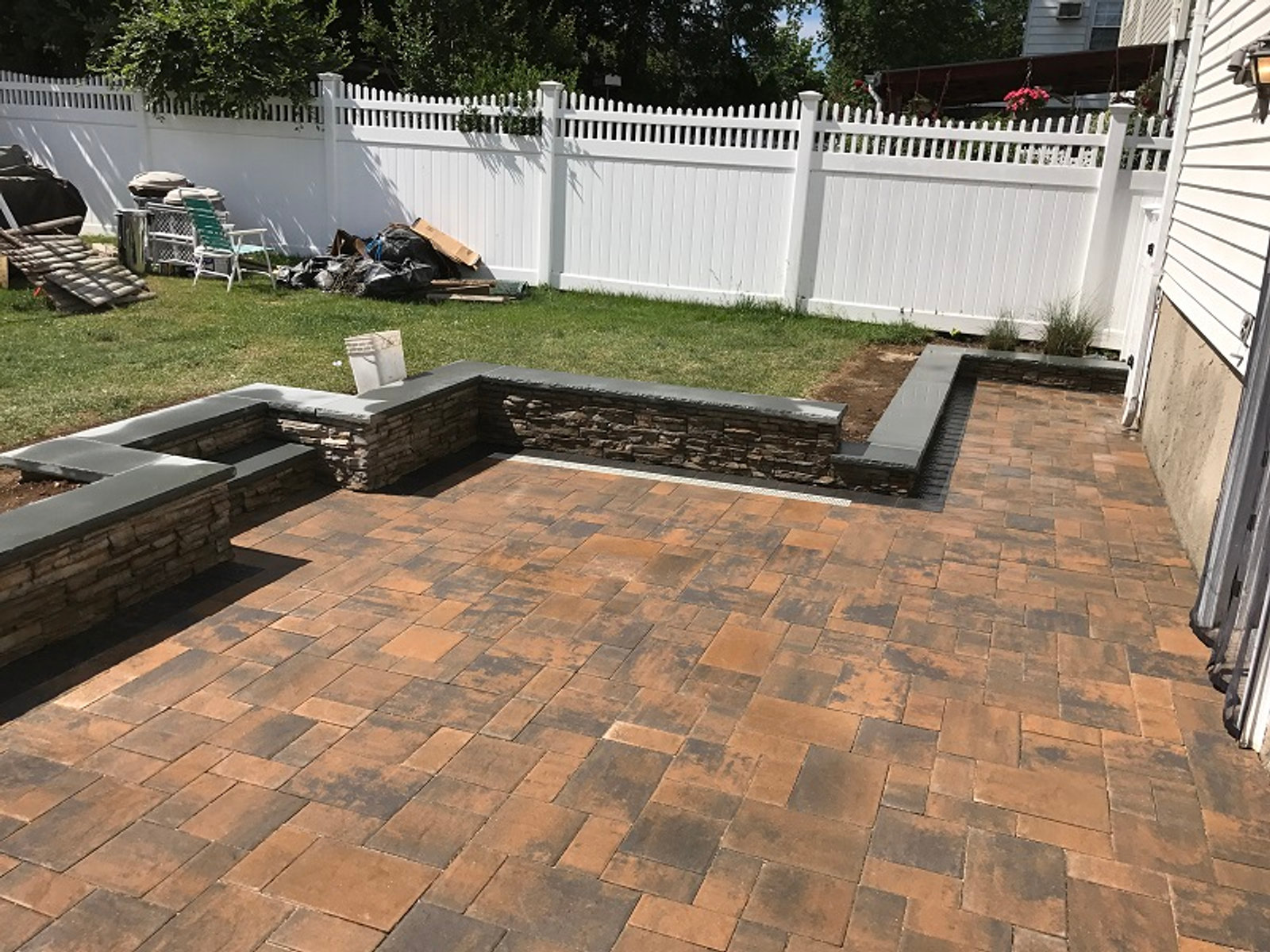 Brick paver patio with white PVC fencing and retaining wall