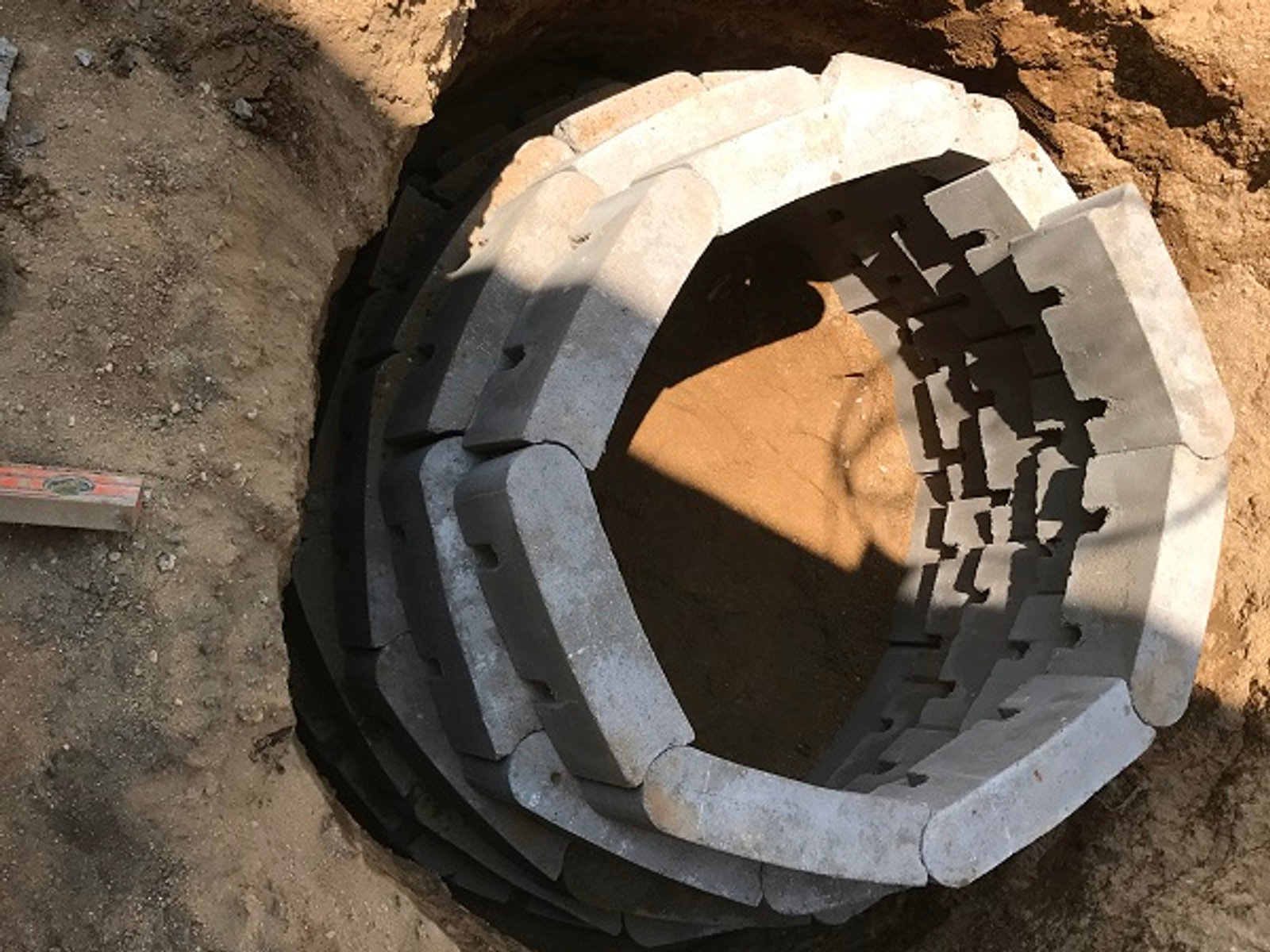 Circular fire pit ring being set into a paver patio