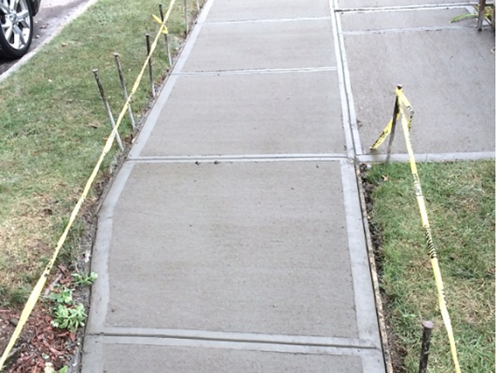 New concrete sidewalk with expansion joints, curing