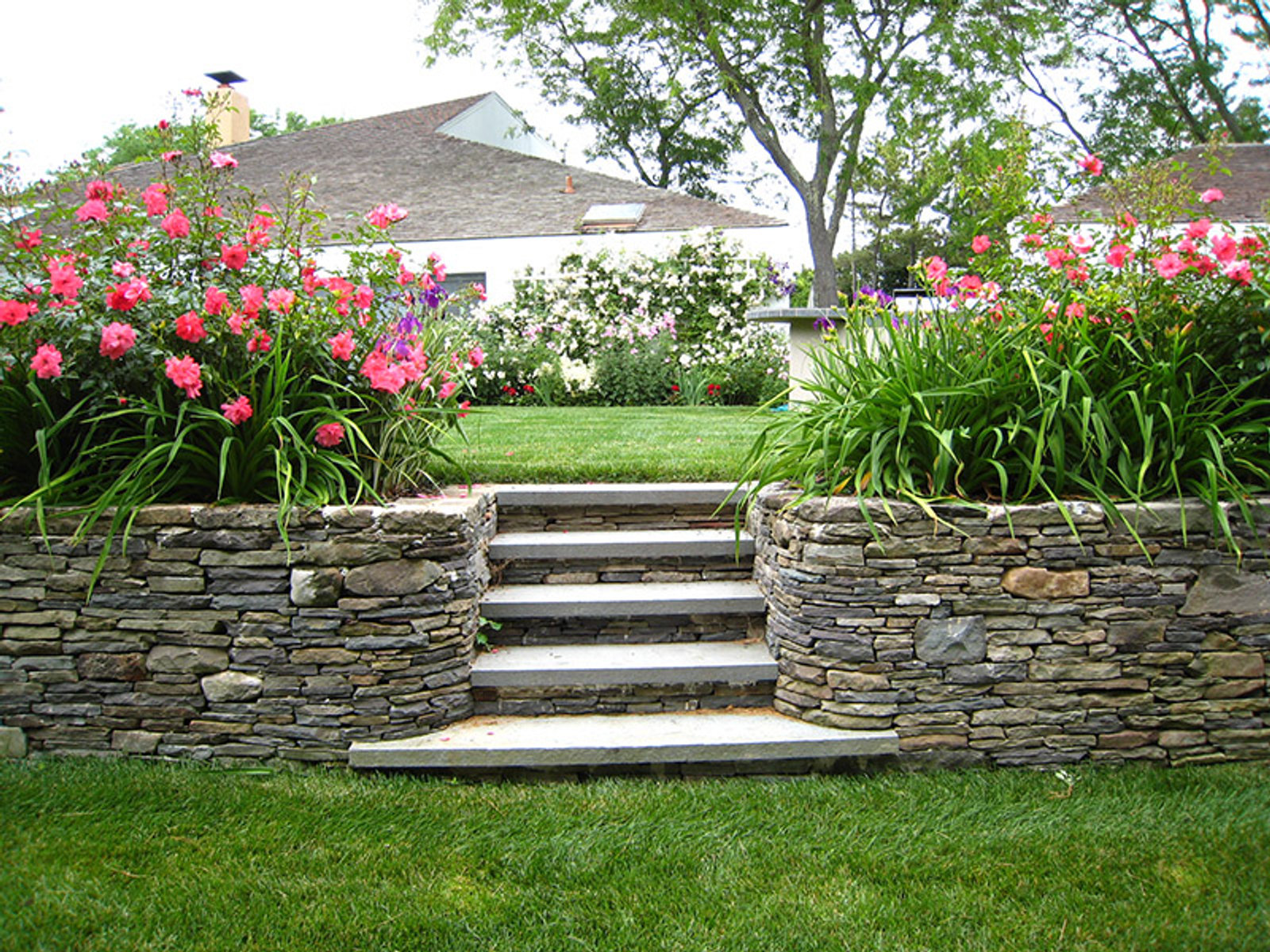 Cultured stone retaining wall with steps and flower beds